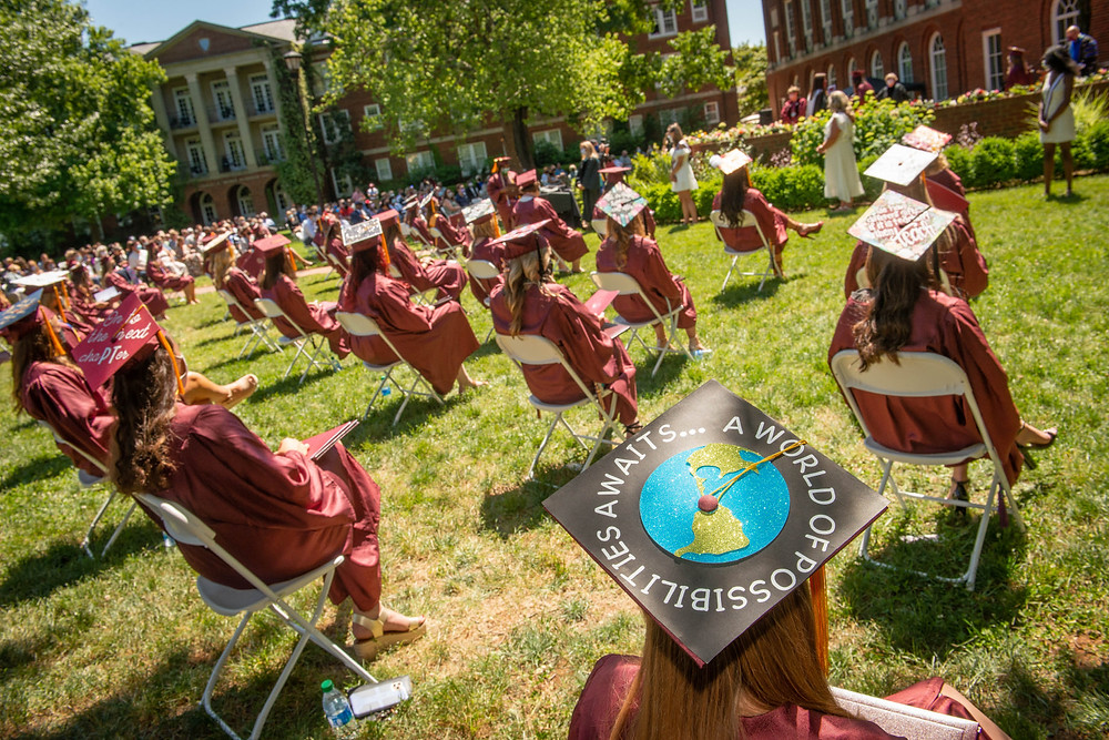 Graduating students sitting behind Johnson Hall in their caps and gowns