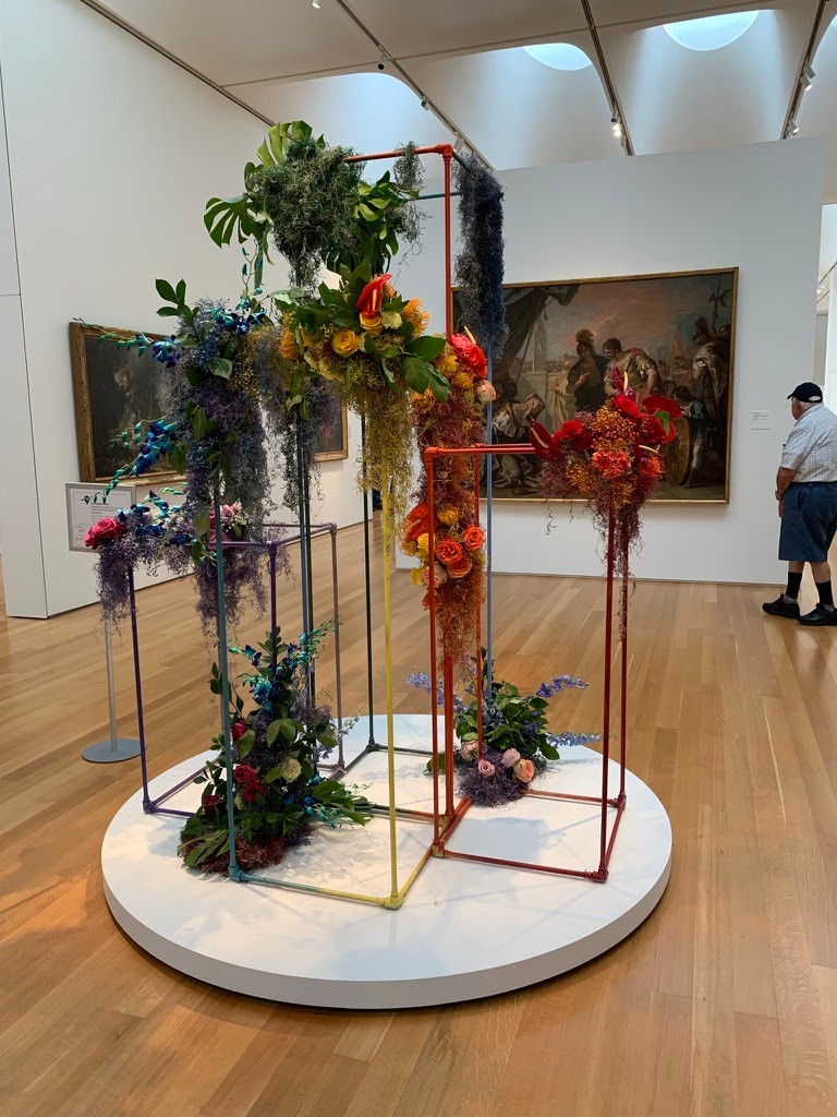 Rainbow colored scaffolding holding up similarly colored flower arrangements