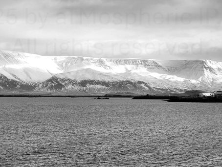 A photo of the ocean with snowcapped mountains in the distance.