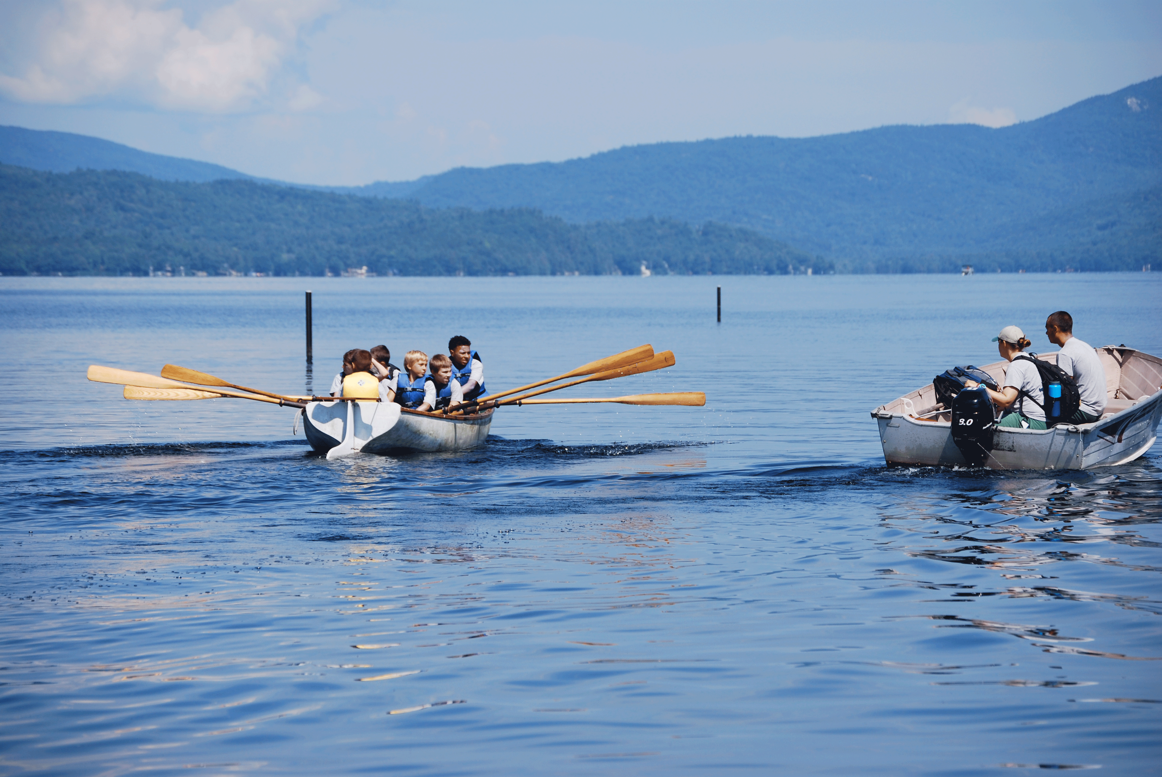 Boys rowing a boat on a lake.