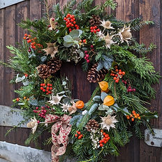 red and green traditional christmas wreath hung on a barn door