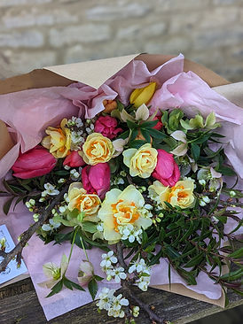 Jolly mix of double daffodils and pink tulips with spring blossom, wrapped in sustainable 