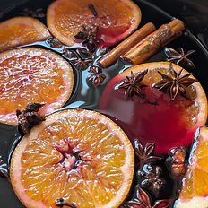 mulled wine simmering with fresh orange slices, cinnamon sticks and star anise