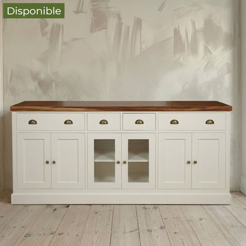 Aparador buffet grande lacado en blanco con encimera de madera natural oscura, seis cajones con tiradores de concha de bronce y puertas con vitrina central sobre suelo de madera clara