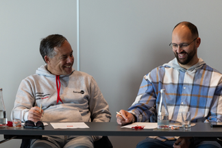 Two team members smile and fill in their bingo cards while participating in the quarterly meeting activity.