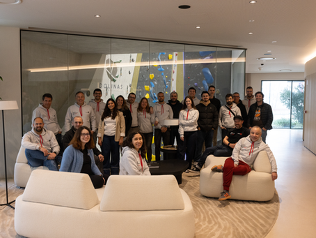 Focus BC team members pose together in a modern lounge area at Dolinas Climbing Hotel, with an indoor climbing wall visible behind them.