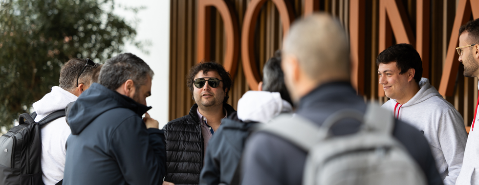 Team members stand chatting outside the entrance of Dolinas Climbing Hotel beneath the hotel’s large sign.