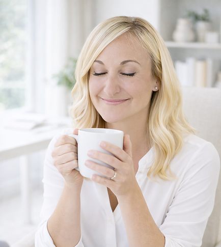 Amy traugh sitting with her eyes closed and holding a cup of coffee at her desk