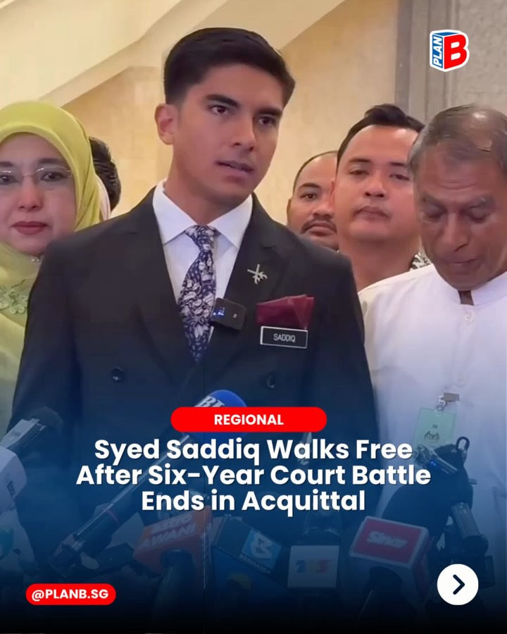 Man in suit speaks at a press scrum with microphones and supporters behind; headline reads Syed Saddiq walks free after acquittal.