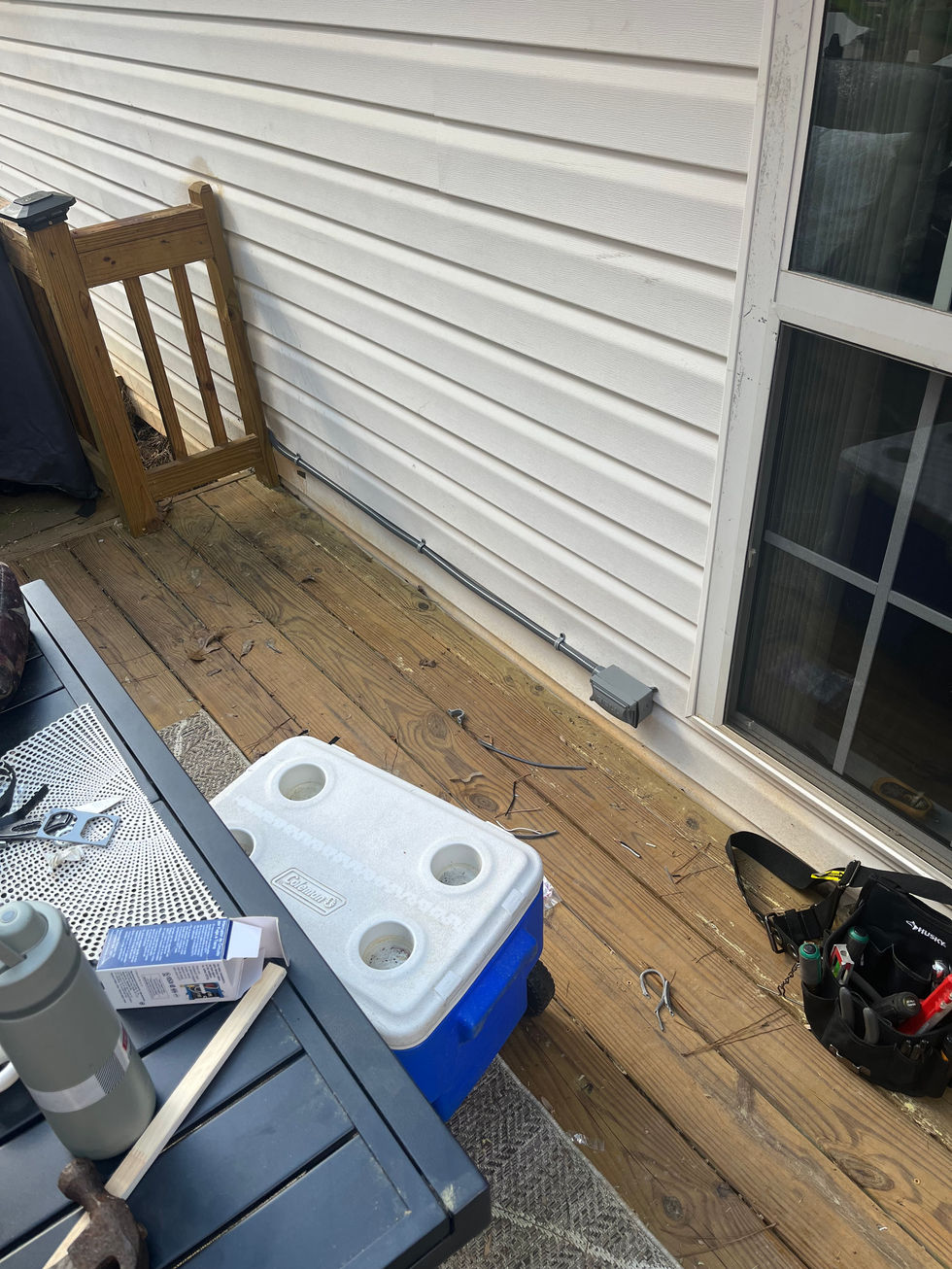 Grey electrical conduit running along house siding on wooden deck for outdoor power project Acworth GA.