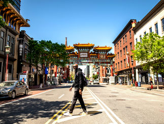 Limin' Professionals Luxury Concierge CEO, Ronald G. Victor, crossing the street in front of a China Town structure in Washington, DC