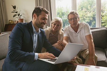 active-senior-couple-discussing-with-real-estate-agent-laptop-living-room.jpg