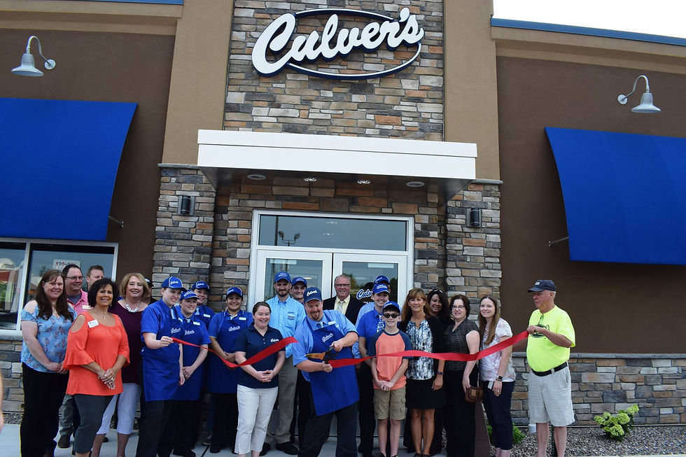 A group celebrates a new restaurant's opening with a ribbon cutting event.