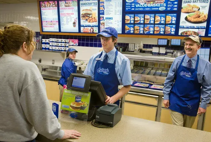 Fast food counter with employees and menu boards, emphasizing customer service experience.