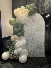 Sage green white and cream balloon garland display with clear bubble balloons frame arched floral patterned backdrop