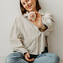 Frau im Schneidersitz, zeigt eine gehäkelte Brust 