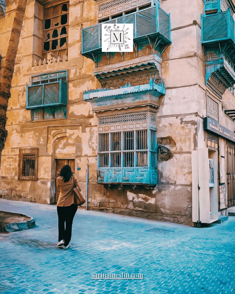 Woman walks by an old building with blue balconies in a historic district. Warm tones, intricate patterns, and website text in the image.
