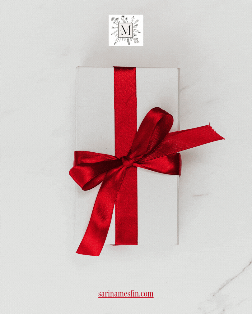White gift box with a red ribbon bow on a marble surface. Logo and text "sarinamesfin.com" at the top and bottom. Elegant and festive.