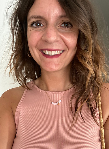 Portrait de Pauline Calonne souriante, éducateur spécialisé libéral, portant un haut rose sans manches, devant un fond clair.