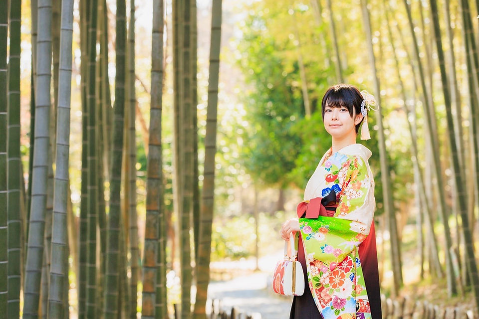 満開の桜の下、旧吉田茂邸で美しく着飾った姉妹が笑顔で並ぶ卒業記念の家族写真。春のやわらかな光に包まれた、家族の温かな思い出を写した一枚。