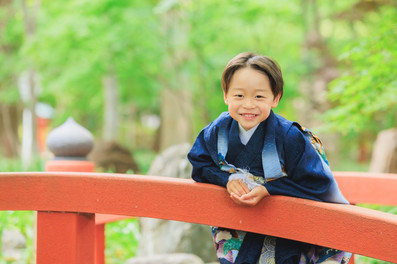 九品仏浄真寺の赤い橋で笑顔を見せる羽織袴姿の男の子