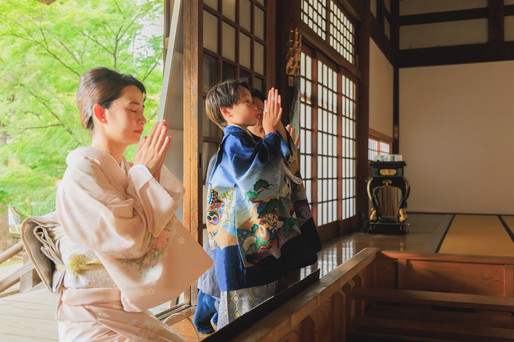九品仏浄真寺のお堂で母親と一緒に手を合わせる七五三の男の子
