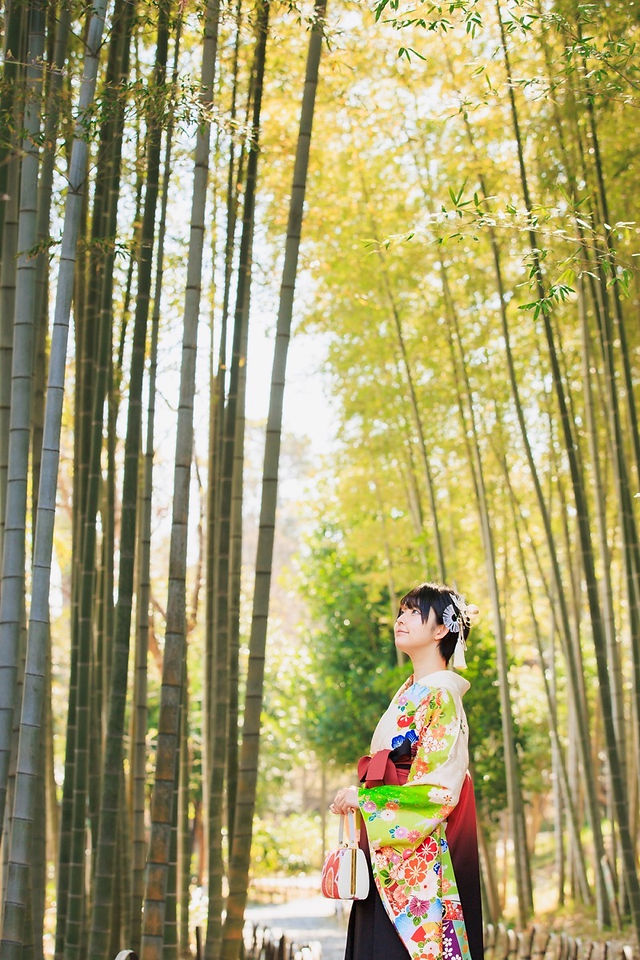 満開の桜の下、旧吉田茂邸で美しく着飾った姉妹が笑顔で並ぶ卒業記念の家族写真。春のやわらかな光に包まれた、家族の温かな思い出を写した一枚。