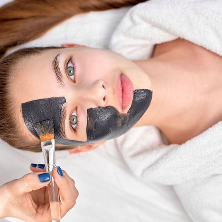 woman-relaxing-with-charcoal-facial-mask-cropped-professional-beautician-applying-face.jpg