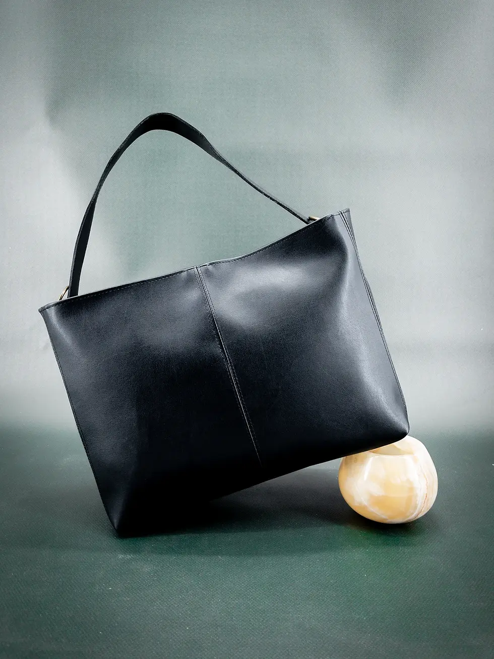 The vegan Lubay Ieper 30 bag in black, seen from a slight angle on a dark green background.
