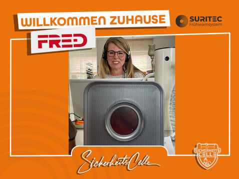 Eine Kundin von SicherheitsCelle arbeitet am Laptop mit Headset. Vor ihr steht ein FR.ED Frühwarnsystem. Text: Willkommen Zuhause FR.ED, Logos von Suritec und SicherheitsCelle.