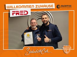 Björn Emanuelsson von SicherheitsCelle erhält eine Urkunde und Auszeichnung bei Suritec. Text: Willkommen Zuhause FR.ED, Logos von Suritec und SicherheitsCelle.