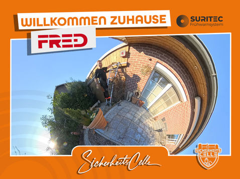 Björn Emanuelsson von SicherheitsCelle montiert ein FR.ED Frühwarnsystem an einer Hauswand in Eschede. Text: Willkommen Zuhause FR.ED, Logos von Suritec und SicherheitsCelle.