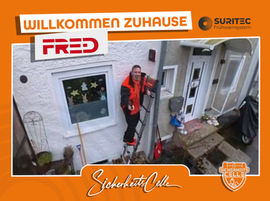 Björn Emanuelsson von SicherheitsCelle montiert ein FR.ED Frühwarnsystem an einer Hauswand in Klein Hehlen/ Celle/ Niedersachsen Text: Willkommen Zuhause FR.ED, Logos von Suritec und SicherheitsCelle.