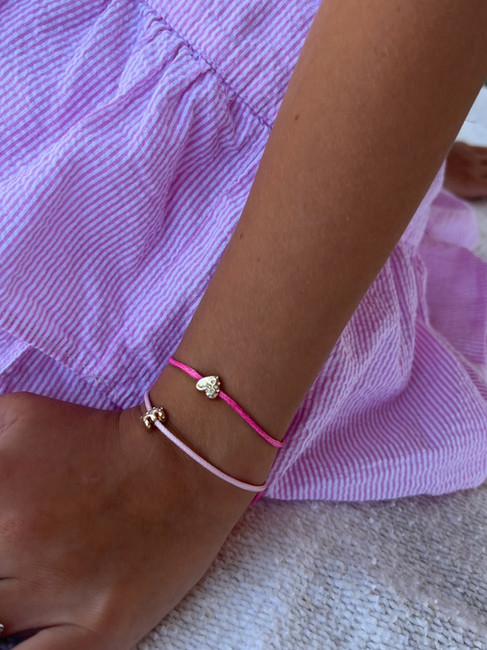 Girl wearing personalized BaubleBar jewelry in gold, showcasing her initials.