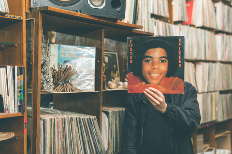 Person holding Michael Jackson album cover over face in a record store