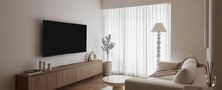 Cozy Scandinavian living room featuring a floating timber TV console, cream upholstered sofa, circular coffee table, and soft sheer window drapes.