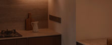 Warmly lit kitchen counter setup with open book display and dark timber cabinetry in a modern interior.