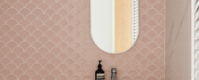 Playful modern bathroom vanity featuring pink scallop wall tiles, fluted vanity storage, white basin, and oval mirror.