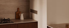 Kitchen counter corner featuring dark wood joinery backsplash tiles and compact kitchen appliances.