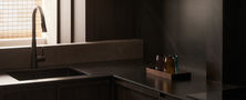 Modern Oriental kitchen design with dark timber cabinets black countertop stone sink and woven bamboo window blinds.