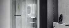 Contemporary shower stall featuring frameless glass enclosure, dark marble wall tiles, matte black rain shower set, and built-in bench.