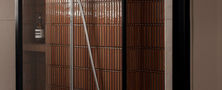 Modern shower enclosure featuring dark vertical wall tiles glass partition door and sleek shower fittings.