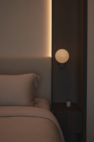 A close-up of a bed with a soft headboard and a round glowing wall light.
Image 8: Master Bedroom Nook