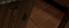 Close view of Dark Japandi foyer floor featuring dark square floor tiles and metallic luggage decor piece.
