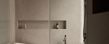 Warm neutral Light Resort Japandi bathroom vanity featuring a stone sink dark wall faucet and oval illuminated mirror.