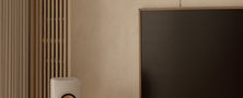 Close view of vertical timber slat wall panelling adjacent to a wall mounted television and minimalist speaker stand.