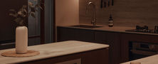 Close view of a dark timber kitchen island with warm backlight LED strips and minimal countertop decor.