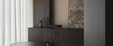 Cozy minimalist dining nook featuring dark timber bench seating, warm cove lighting, and subtle wall sconces.