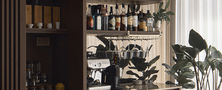 Custom dark wood home bar counter featuring illuminated open glass shelving liquor bottle display and wine chiller.