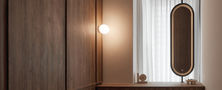 Scandinavian walk-in wardrobe and vanity nook featuring full-height timber cabinets, a floating dressing table, stool, and suspended backlit oval mirror.